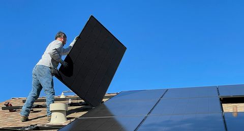 Arbeiter montiert eine Solaranlage auf ein Dach